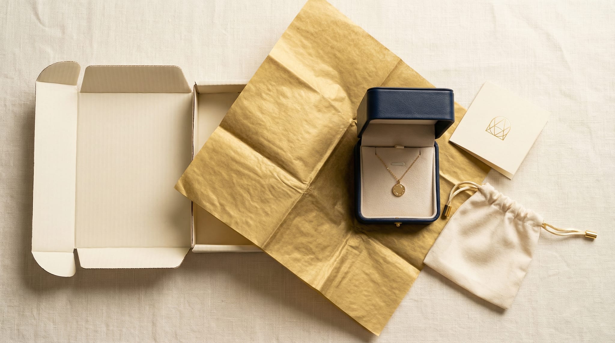 E-commerce jewelry shipping layers — branded mailer, tissue wrap, insert card, and custom jewelry box arranged to show the unboxing sequence