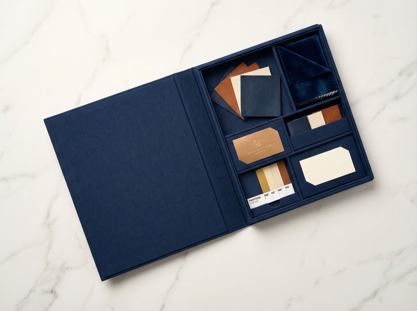 Open branded sample kit with leather swatches in navy, cognac and cream, velvet squares, gold foil sample card, and Pantone chips
